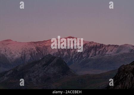 Last sun of the day on snow covered Snowdon Mountain. Landscape Stock Photo