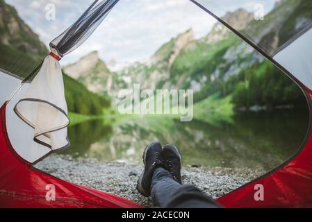 Woman's feet sticking out of tent by Seealpsee lake in Appenzell Alps, Switzerland Stock Photo