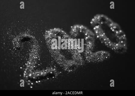 2020 shiny silver sparkles pattern on black table. Stock Photo