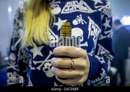 Young girl holds in hand an electronic cigarette at a vape shop Stock Photo