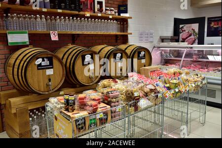 Bulk wine in wooden casks with rows of empty bottles to fill yourself in “IS” supermarket, Porec, Croatia, snacks in front. Saves the environment. Stock Photo
