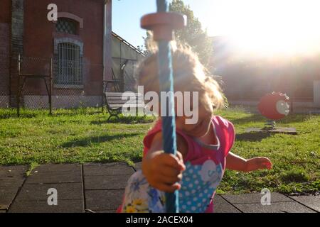 Little girl climbs on rope in the playground. Childhood concept. Growth concept. Stock Photo