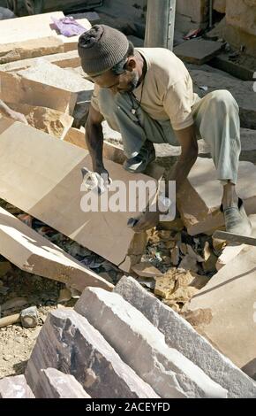 Shaping stone. Builder using a hammer and chisel to cut slabs of stone. Photographed in Rajasthan, India. Stock Photo