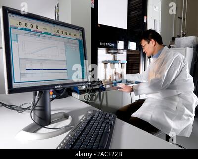 Materials testing. Technician testing an object in a typical static test machine (centre, large vertical). Static testing involves subjecting a materi Stock Photo