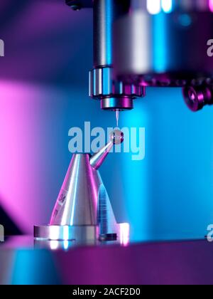 3D measurement of an object. Close-up of a coordinate measurement machine (top, black) measuring the dimensions of a small sphere (black, centre). Mac Stock Photo