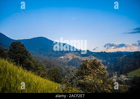 paisaje hermoso de atardecer con bosques y siembras de trigo y montañas de cajola Quetzaltenango, casas de personas en el valle Stock Photo