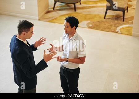 Multi-ethnic serious business people trying to prove their point of view to each other, talking and actively gesturing Stock Photo