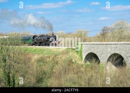 Black railway and green coach pass the Corfe bridge, Dorset, UK Stock Photo