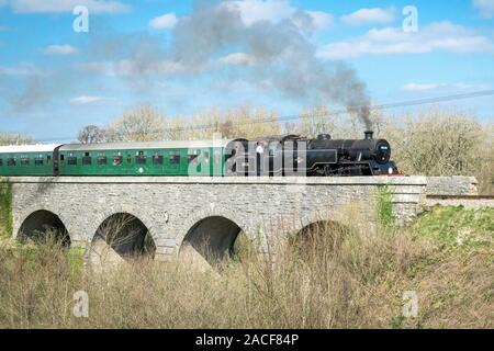 Black railway and green coach pass the Corfe bridge, Dorset, UK Stock Photo