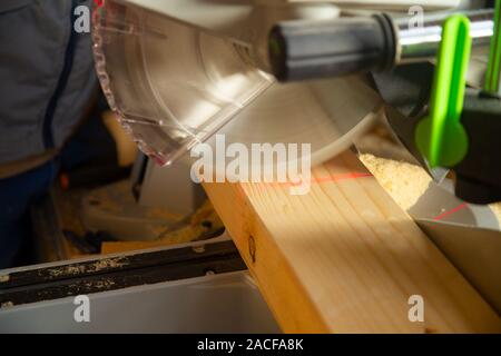 Closeup of carpenter cutting a piece of wood with a modern table saw Stock Photo