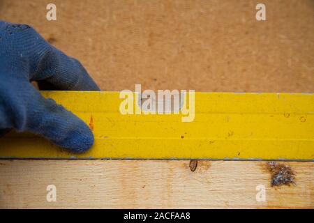 Hand of a carpenter working with a bubble level on a wooden slat Stock Photo