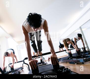 Pilates class. People using pilates exercise equipment during a class. Stock Photo
