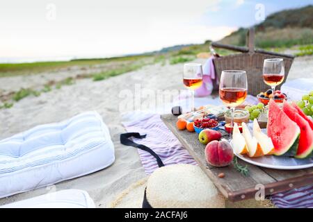 Picnic on the beach at sunset in the style of boho. Food and drink, relax, holiday concept Stock Photo