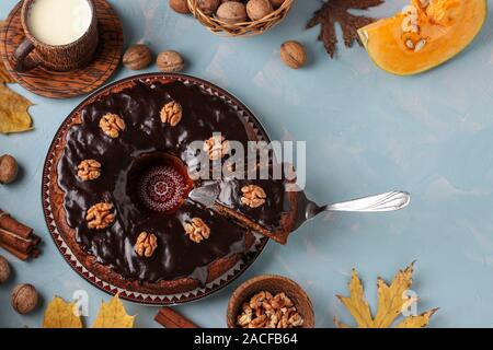Homemade pumpkin muffin, with a cut out slice, decorated with chocolate icing and walnuts on a light blue background, Copy space, horizontal Stock Photo