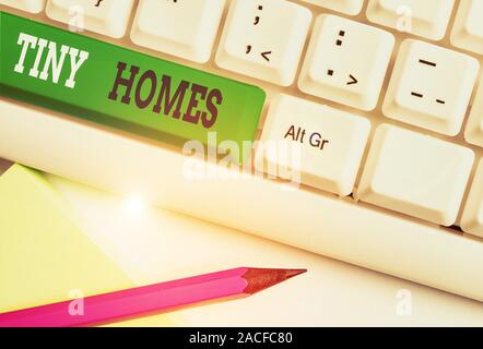Conceptual hand writing showing Tiny Homes. Concept meaning houses contain one room only or two and small entrance Cheap White pc keyboard with note p Stock Photo