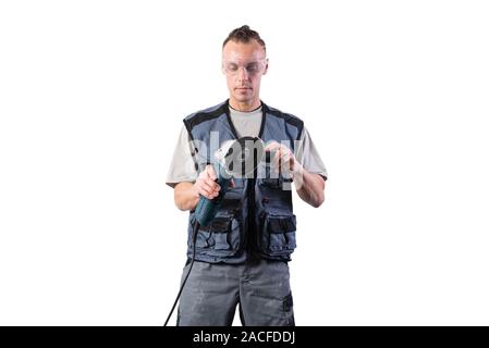 The builder in goggles, with an angle grinder in his hands. Stock Photo