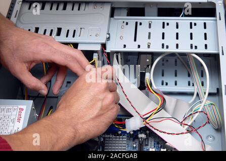 Fixing a computer. Computer technician working on the inner parts of a PC. A hard-drive (black, centre right) can be seen along with the motherboard ( Stock Photo