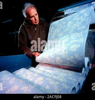 Wallpaper manufacture. Worker inspecting wallpaper as it comes off the printing press. This wallpaper is made using water based paints and traditional Stock Photo