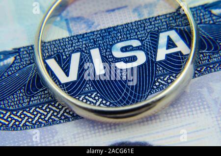Macro photo of US visa sticker in a passport and a gold ring on top of. Conceptual macro photo for 'obtaining the american visa through the marriage'. Stock Photo