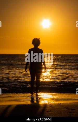 Silhouette of a woman standing on beach at sunset, Brazil Stock Photo