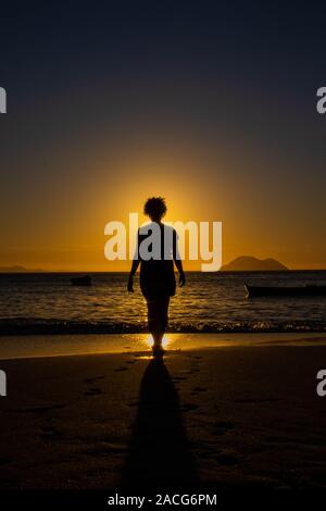 Silhouette of a woman walking on beach at sunset, Brazil Stock Photo