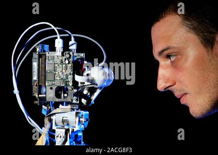 iCub robot and researcher. The iCub is a small humanoid robot designed by the RobotCub Consortium of scientists from European universities. It is inte Stock Photo