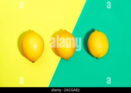 Creative pattern made of lemons on bright yellow and trendy green blue background. Fruit minimal concept. Top view, flat lay, close up. Stock Photo