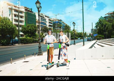 Young couple on vacation having fun driving electric scooter through the city, Athens Greece. Couple is fun, exploring nice places. The best travel destinations. Stock Photo