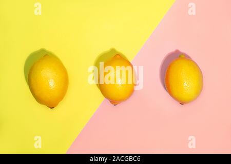 Creative pattern made of lemons on bright yellow and pastel pink background. Fruit minimal concept. Top view, flat lay, close up. Stock Photo