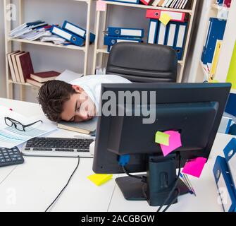 Businessman working in the office with piles of books and papers doing paperwork Stock Photo