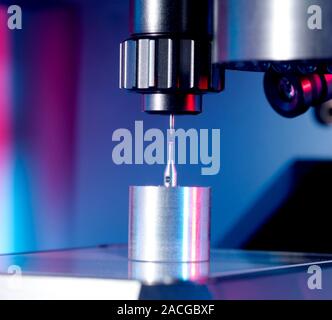 3D measurement of an object. Close-up of a coordinate measurement machine (top, black) measuring the dimensions of a small sphere (pink, centre) mount Stock Photo