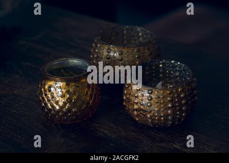 Three burning candles in golden ornamental candle holder wiith copy space against dark background Stock Photo