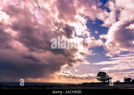 Dramatic storm clouds covering the sun and pouring rain on the Pacific Ocean coastline, California Stock Photo
