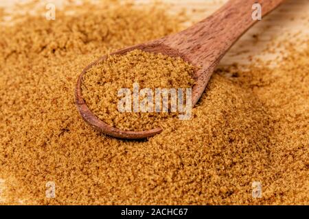 Wooden spoon full of sweet light brown sugar on a wooden background Stock Photo