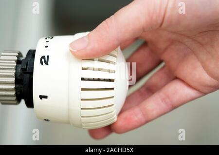 Thermostatic radiator valve. Person adjusting a thermostatic radiator valve (TRV) on a domestic radiator. TRVs adjust the temperature output from a ra Stock Photo