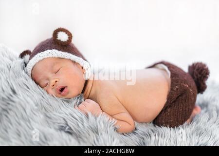 newborn baby in bear hat sleeping on a fur bed Stock Photo