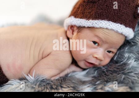 newborn baby in bear hat on a fur bed Stock Photo