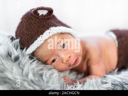 newborn baby in bear hat on a fur bed Stock Photo