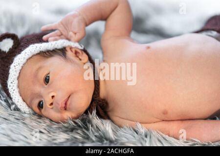 newborn baby in bear hat on a fur bed Stock Photo