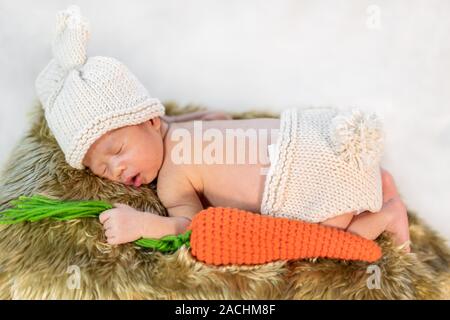 newborn baby in bunny costume sleeping on a fur bed Stock Photo