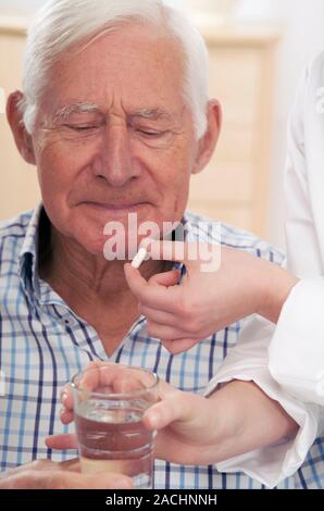 Geriatric care. Young woman helping an older man to take his medication. Stock Photo