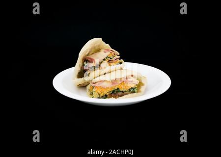 Pita pocket bread stuffed with cheese and sliced cooked ham, Malabar spinach and carrot frittata (fried beaten eggs), ready to eat Stock Photo