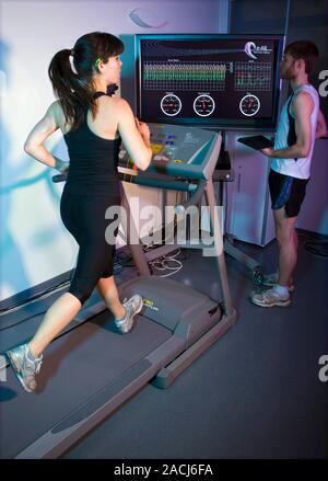 Athletics research. Researcher on a treadmill, wearing (on her ear) and testing the Ear Activity Recognition (e-AR) sensor as part of the Running Moti Stock Photo
