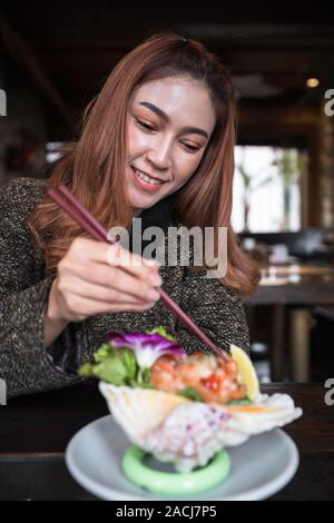 woman eating salmon sashimi spicy salad in the restaurant Stock Photo