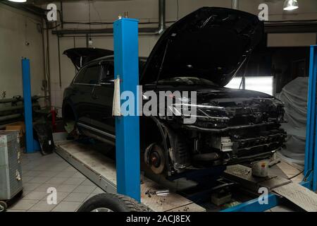 A used car raised on a lift for repair and under it a detached engine ...
