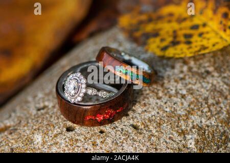 Engagement and wooden fire opal wedding rings in a fall background Stock Photo