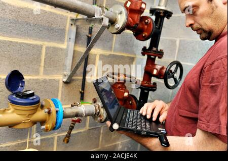 Laptop use in engineering. Technician working on a laptop. A dongle is plugged into the laptop, allowing wireless computing over a mobile telephone ne Stock Photo