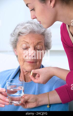 Geriatric care. Young woman helping an older woman to take her medication. Stock Photo