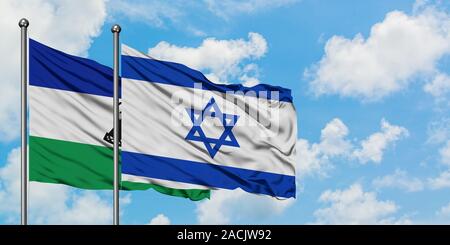 Lesotho and Israel flag waving in the wind against white cloudy blue sky together. Diplomacy concept, international relations. Stock Photo