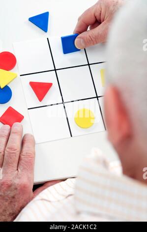 Alzheimer's disease test. Elderly man doing a puzzle during a test for Alzheimer's disease. This is a condition in which there is a gradual loss of me Stock Photo